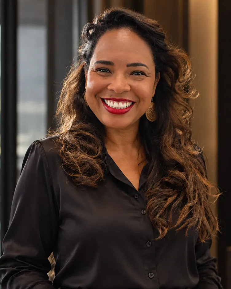 Anna Claudia Bacelar, contadora, de camisa preta, sorrindo no escritório